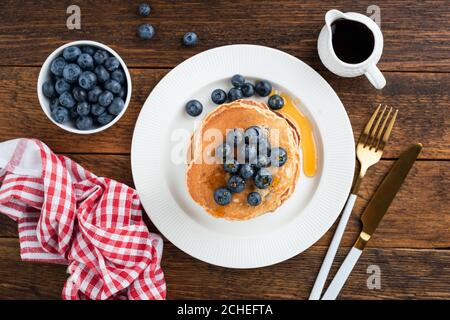 Pancake con mirtilli e sciroppo d'acero su un tavolo di legno sfondo, vista dall'alto Foto Stock