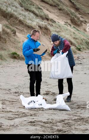 Attivisti della beneficenza britannica per la conservazione del mare Surfers Against Sewage, (da sinistra a destra) Harry Dennis e Rachel Yates stanno chiedendo volontari in tutto il Regno Unito per aiutare a pulire le spiagge, le montagne, le strade e i corsi d'acqua delle nazioni, e tenerli puliti dalla plastica, a Perranporth, Cornovaglia. Foto Stock