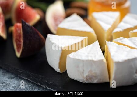 Formaggio camembert a fette e fichi su ardesia nera, vista closeup. Piatto di formaggi gourmet Foto Stock