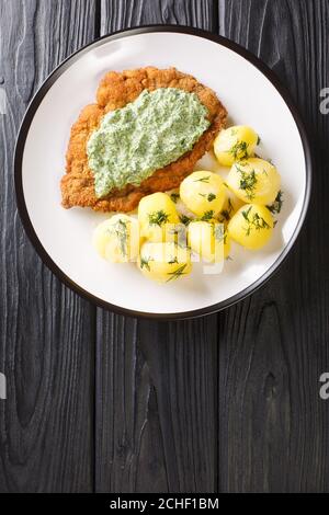 Cucina tradizionale di Francoforte schnitzel con patate novelle bollite e salsa verde primo piano in un piatto sul tavolo. Vista dall'alto verticale Foto Stock