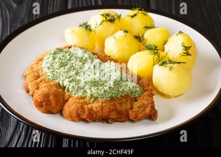 Schnitzel impanato con patate bollite e salsa verde di Francoforte primo piano in un piatto sul tavolo. Orizzontale Foto Stock