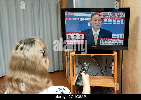 Woman guarda la conferenza stampa trasmessa in diretta dalla televisione giapponese da Yoshihide Suga, il nuovo leader del Partito Liberale democratico (LDP). Foto Stock