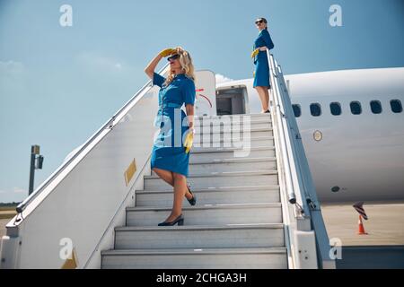 Due bellissime stewardesses in piedi sulle scale dell'aeroplano Foto Stock