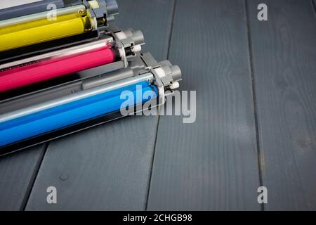 Tre cartucce di toner usate in una stampante laser a colori su sfondo grigio in legno per il riciclaggio Foto Stock