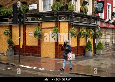 Una donna passa davanti a un pub a bordo nel nord di Londra, mentre il Regno Unito continua a bloccarsi per aiutare a frenare la diffusione del coronavirus. Foto Stock