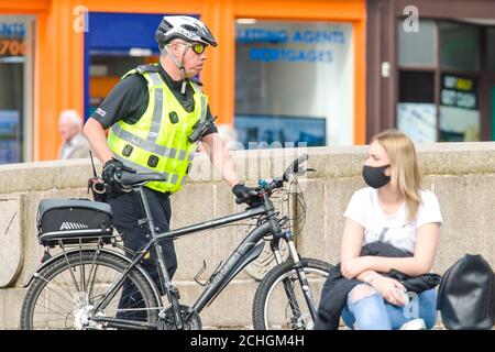 Un poliziotto è avvistato sulla High Street dal centro della città di Paisley, che, comprese altre città del Renfrewshire, ha avuto ulteriori misure di blocco aggiunto a mezzanotte la scorsa notte. A causa di un picco nei casi di Covid-19. Credito: Euan Cherry Foto Stock