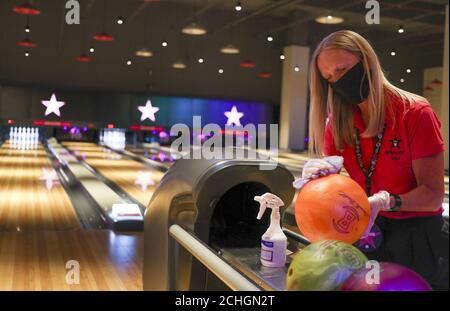 SOTTOPOSTO A EMBARGO AL 0001 MARTEDÌ 16 GIUGNO UN membro dello staff dell'Hollywood Bowl di Thurrock, Essex, pulisce le palle da bowling. Una delle numerose misure di sicurezza sul luogo di lavoro che si stanno mettendo in atto in attesa delle future linee guida del governo britannico per quanto riguarda la riapertura delle imprese di svago. Foto Stock