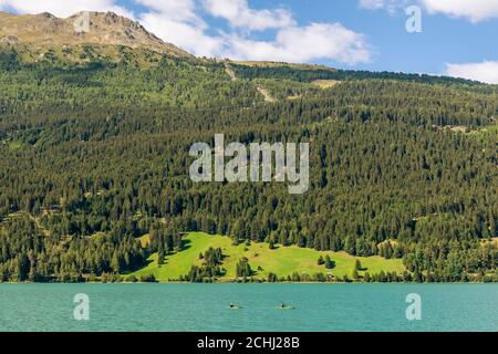 Due canoe sul Lago di Resia nel magnifico scenario alpino che circonda la zona, Curon (Graun), Alto Adige, Italia Foto Stock