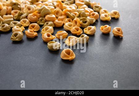 Concetto di cucina della pasta. Tortellini freschi fatti in casa su fondo di pietra nera, vista closeup, spazio copia Foto Stock