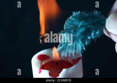 Primo piano di una piuma che brucia su una candela Foto Stock