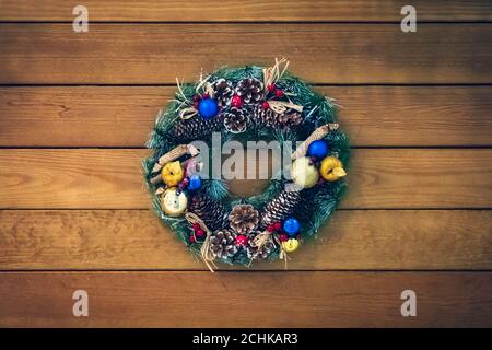 Corona di Natale di coni, rami di abete rosso e bacche, decorazioni di Capodanno. Bella corona di abete rosso con coni, palle e frutta. Foto Stock