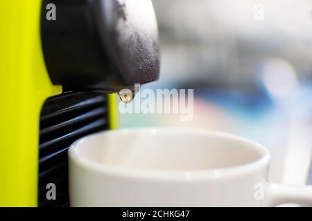 Macchina per il caffè che versa lentamente il liquido in una tazza in una cucina casalinga. Goccia che cade nella tazza Foto Stock