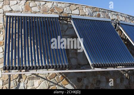 Impianto solare di riscaldamento dell'acqua installato sulla parete o sul tetto della casa. 3 pannelli di tubi coassiali in vetro con acqua per accumulare calore. Vista laterale. Envir concettuale Foto Stock