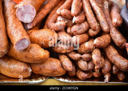 Deliziosi pezzetti di salsiccia affumicata esposte per la vendita nel mercato. Messa a fuoco selettiva e piccole profondità di campo Foto Stock