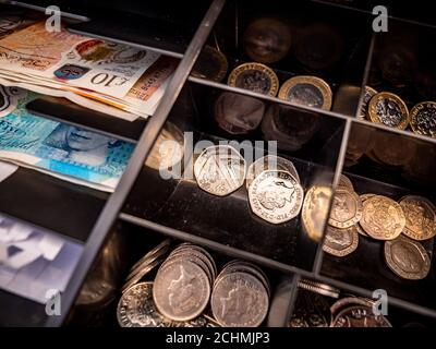 Fluttuazione del registro di cassa del Regno Unito. Full Frame dettaglio vicino sul contenuto di un cassetto cassa con banconote e monete in sterline inglesi. Foto Stock