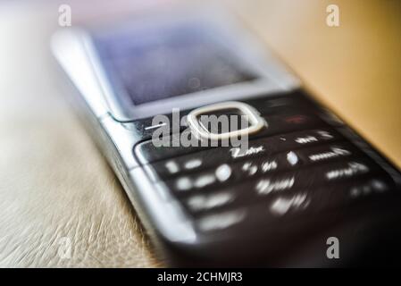 Vecchio telefono su sfondo marrone chiaro. Sfondo sfocato per diversi tipi di applicazioni. Messa a fuoco selettiva Foto Stock