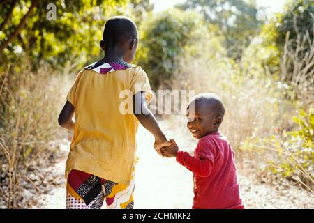 Bambini africani sorridenti camminando all'aperto nella tipica città tribale vicino Bamako, Mali (Africa) Foto Stock