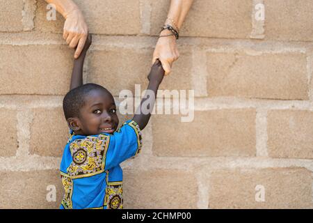 Sorridente African Black Boy ottiene aiuto da White Caucasian Woman Di fronte al muro Foto Stock