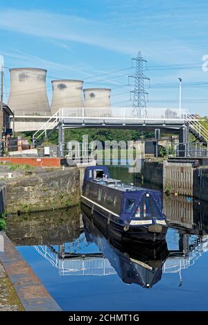 Narrowboat uscire dalla serratura sulla navigazione Aire & Calder, con la centrale di Ferrybridge sullo sfondo, West Yorkshire, Inghilterra Regno Unito Foto Stock