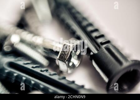 Primo piano degli elementi di fissaggio bulloni, chiodi, viti, rondelle, tasselli, tasselli sfocati sulla parte superiore e inferiore della foto. Foto Stock