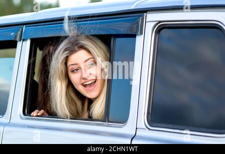 Una ragazza bionda guarda fuori da una finestra aperta dell'automobile. Foto Stock