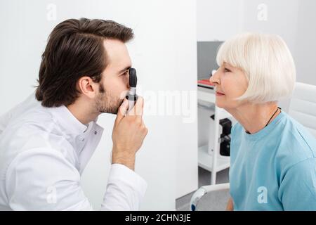 L'optometista che esegue un esame oculare su un paziente utilizzando un oftalmoscopio, la diagnosi della cataratta. Controllo visivo, primo piano Foto Stock