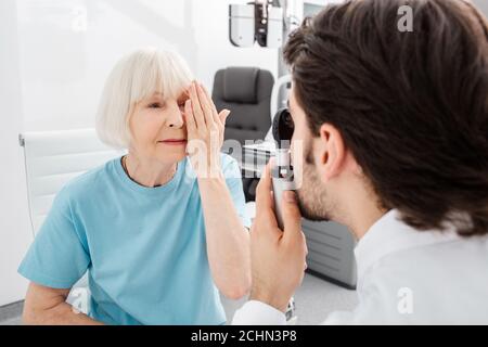 Donna anziana paziente che controlla la visione nell'ufficio dell'ottico. Esame visivo e diagnostica visiva Foto Stock