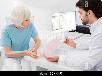 il cardiologo consulta una donna anziana sui risultati di un cardiogramma e di test. Aritmia e malattie cardiache, diagnosi Foto Stock