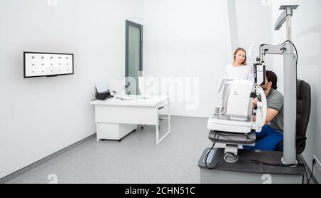 donna oftalmologista con un paziente umano vicino ad apparecchiature oftalmiche in un moderno ufficio oftalmologico. Diagnostica degli occhi Foto Stock