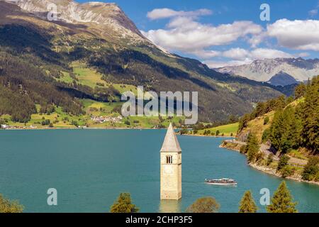 Vista dall'alto di una crociera sul Lago di Resia vicino all'antico campanile sommerso di Curon Venosta, Alto Adige, Italia Foto Stock