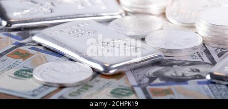 Closeup di barrette d'argento e monete d'argento e 100 dollari fatture Foto Stock