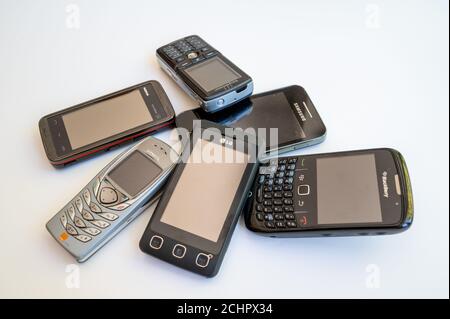 Una selezione di vecchi telefoni cellulari in una pila su sfondo bianco. Foto Stock