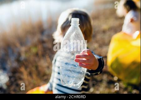 Irriconoscibile bambino piccolo che raccoglie i rifiuti all'aperto in natura, plogging concetto. Foto Stock