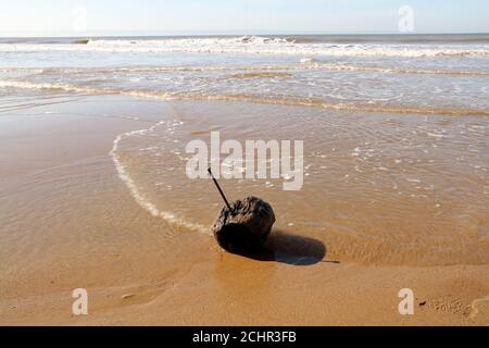 Un bullone in acciaio fortemente corroso con un dado in acciaio inossidabile usurato collegato guidato attraverso un blocco di legno che si infila sulla marea. Foto Stock