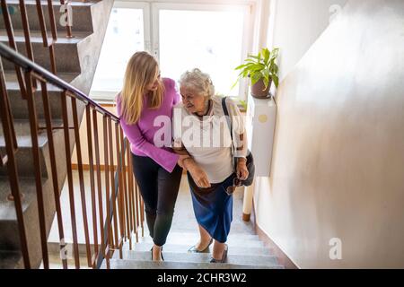 Caregiver che aiuta donna anziana a salire scala Foto Stock