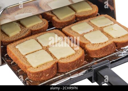 Colpo orizzontale di quattro pezzi di pane di grano macinato che sta per essere spinto nel tostapane e tostato. Foto Stock