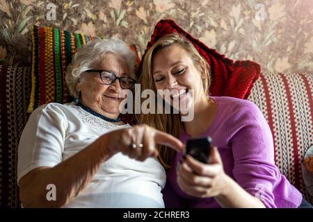 La donna anziana e la nipote adulta che utilizzano lo smartphone insieme Foto Stock