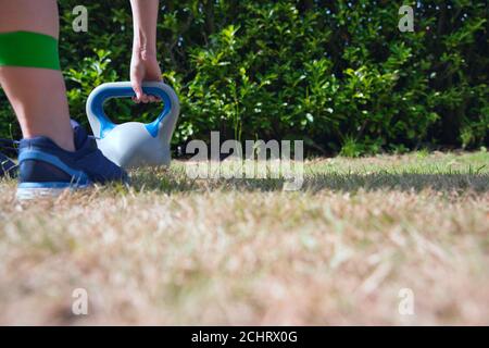 Fitness kettlebell donna cross training esterno su crass sollevamento kettlebells e banda di resistenza per squat Foto Stock