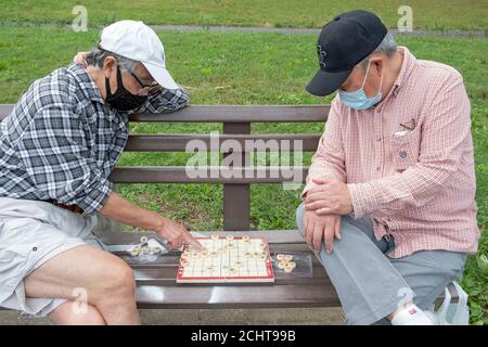 Due uomini cinesi americani più anziani giocano a Xiangpi, talvolta chiamati scacchi cinesi. In un parco a Flushing, Queens, New York City. Foto Stock