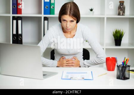 Una donna graziosa sta avvertendo il dolore addominale severo Foto Stock