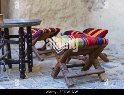 Sedie turche e tavolo esterno con pareti in pietra sullo sfondo Foto Stock