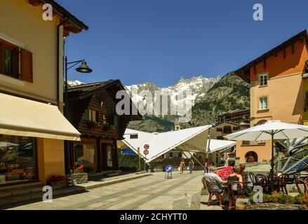 Vista di via Roma nel centro della città alpina ai piedi del massiccio del Monte Bianco con turisti in estate, Courmayeur, Valle d'Aosta, Italia Foto Stock