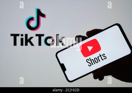 Stafford / UK - Settembre 14 2020: YouTube Shorts il logo dell'app visto sulla silhouette dello smartphone in una mano e il logo TikTok sullo sfondo sfocato. R Foto Stock
