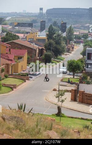 Giovane ragazzo africano che gioca nella strada di un sobborgo residenziale nella cittadina di Soweto, Sudafrica Foto Stock