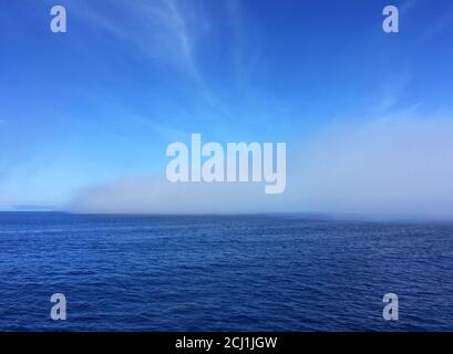 Oceano pacifico costiero al largo di Dunedin, fitta banca nebbia in mare a causa di quasi nessun vento durante il giorno, Nuova Zelanda, Isola del Sud Foto Stock