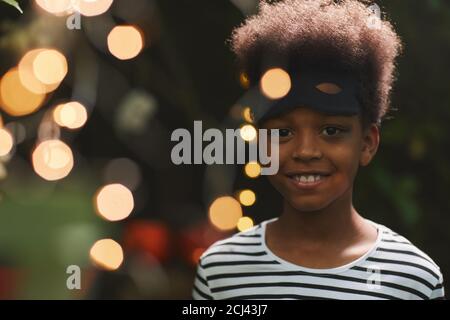 Ritratto di sorridente afroamericano guardando la macchina fotografica durante la festa esterna di Halloween con le luci, copia spazio Foto Stock