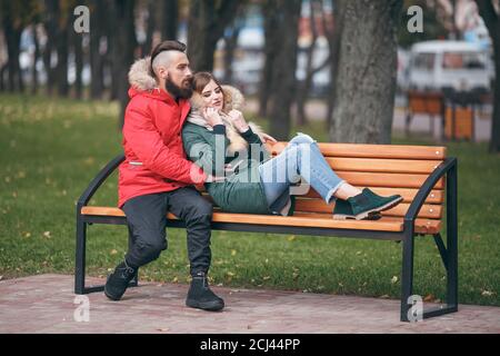 Un ragazzo e una ragazza si riposano su una panchina in un parco autunnale Foto Stock