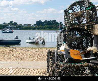 Mudeford Quay, Regno Unito - 16 luglio 2020: Due pescatori che tornano dalla pesca marittima, prendendo la barca su terra asciutta e disimballando le attrezzature Foto Stock