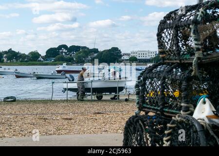 Mudeford Quay, Regno Unito - 16 luglio 2020: Due pescatori che tornano dalla pesca marittima, prendendo la barca su terra asciutta e disimballando le attrezzature Foto Stock