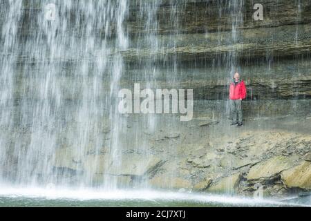 Uomo in giacca rossa dietro le cascate, Bridal Veil Falls, Manitoulin Island, Ontario, Canada Foto Stock